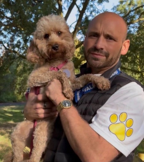 Jack, dog walker at 4 Paw Friend, holding a cockapoo on a walk in South London.