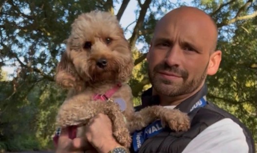 Jack, dog walker at 4 Paw Friend, holding a cockapoo on a walk in South London.