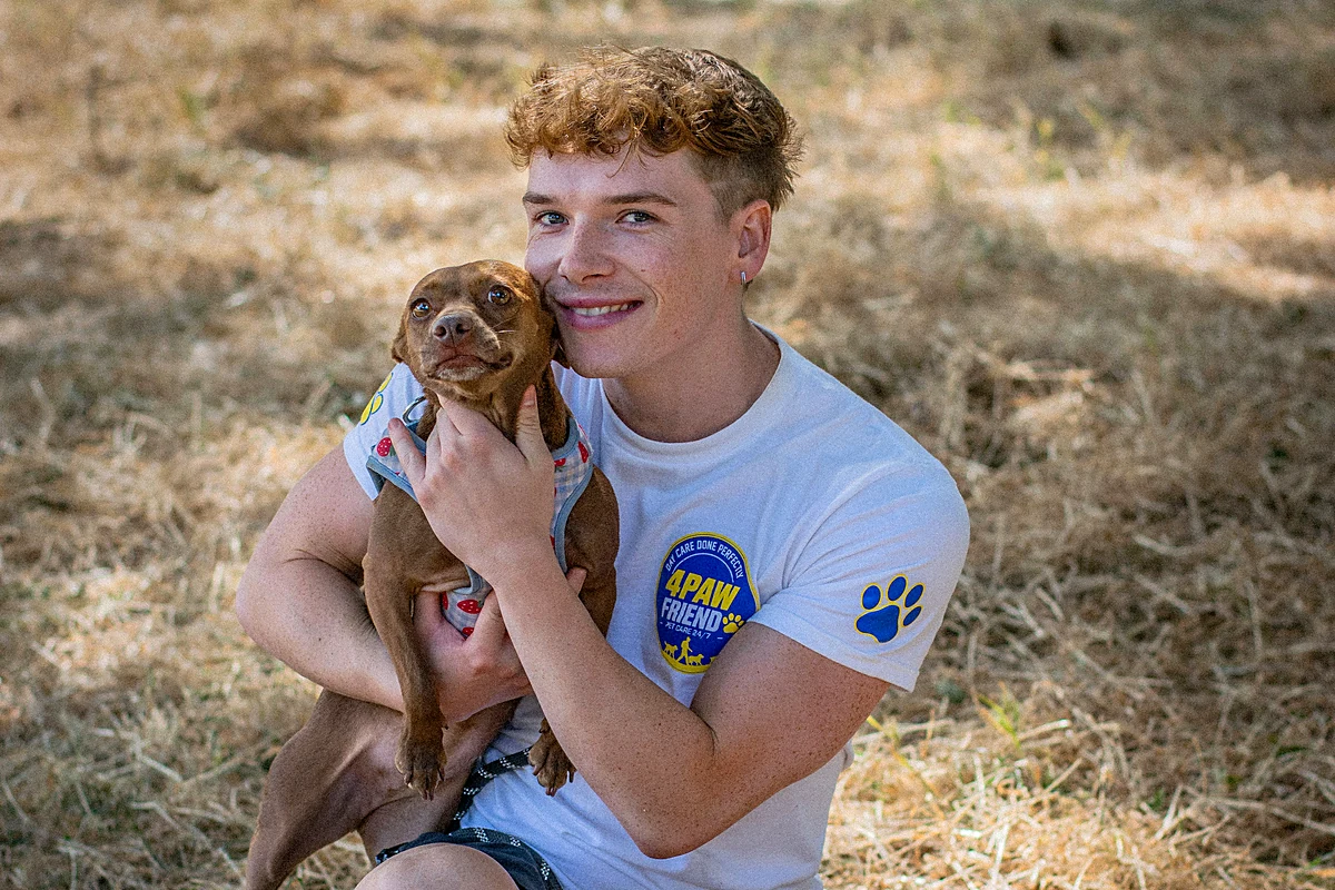A 4 Paw Friend walker holding a small dog in a South London park.